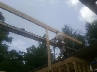 Carpenter setting a ridge beam over a new addition frame — Ice Dam Removal by Roofing Brothers in Stacyville