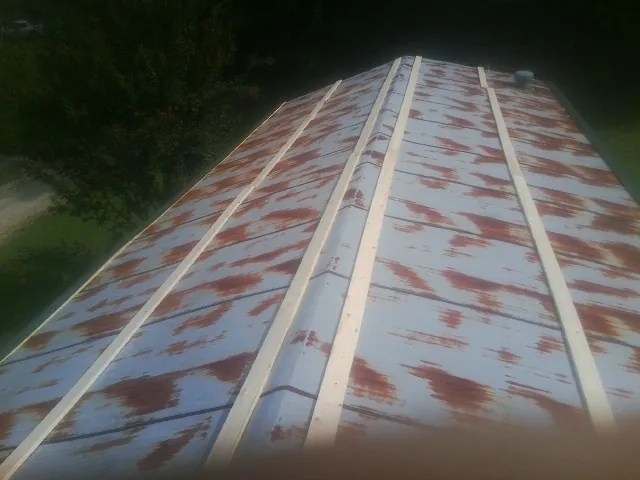Rusted metal roof panels with new wood purlins before replacement in Stacyville