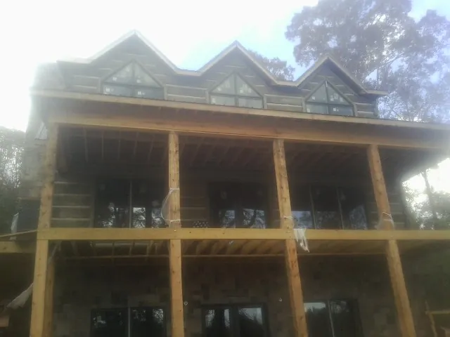 Dormers and porch framing on a large log home under construction — Roof Coating work by our crew in Stacyville