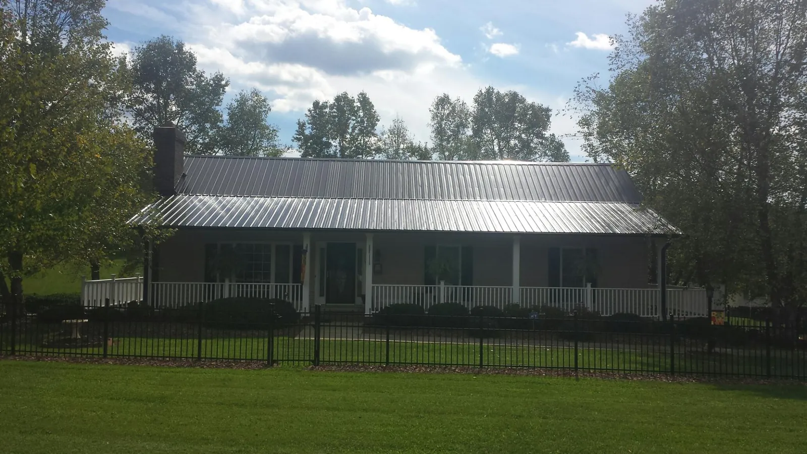Gray metal roof on a brick ranch with a full width front porch — Gutter Guard Installation work by our crew in Stacyville