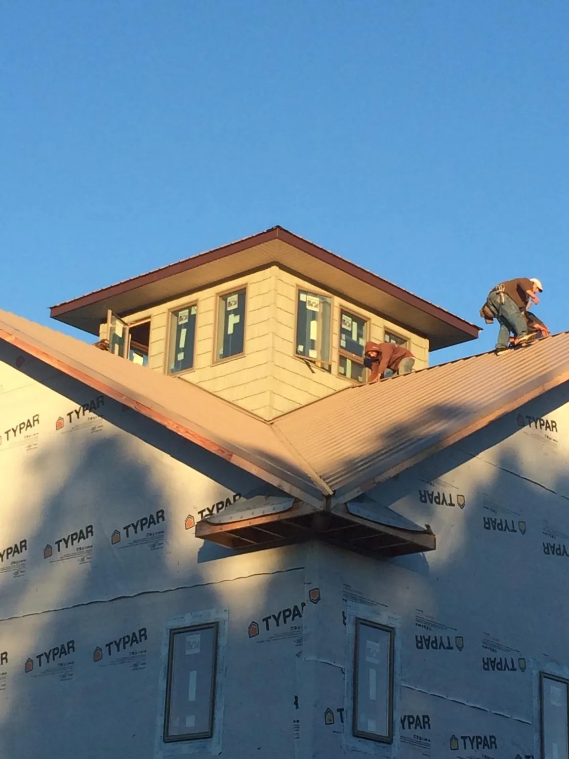 Roofers working around a rooftop cupola on a new metal roof at sunset — Roof Waterproofing in Stacyville by Roofing Brothers